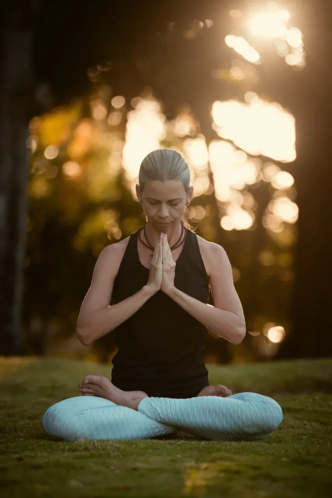 Michelline meditando ao ar livre, com as mãos em prece